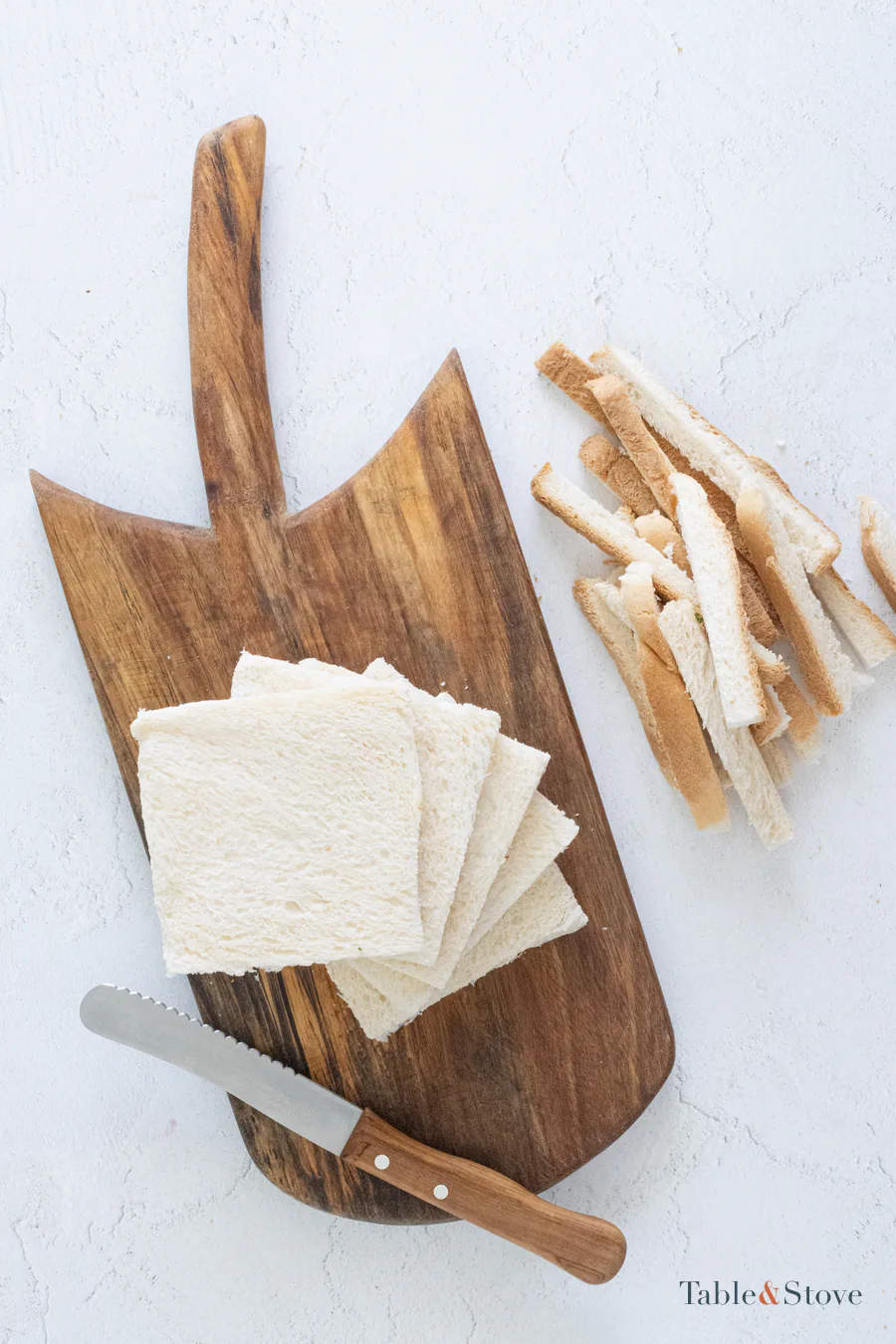 Five crustless white bread slices beside the removed crusts