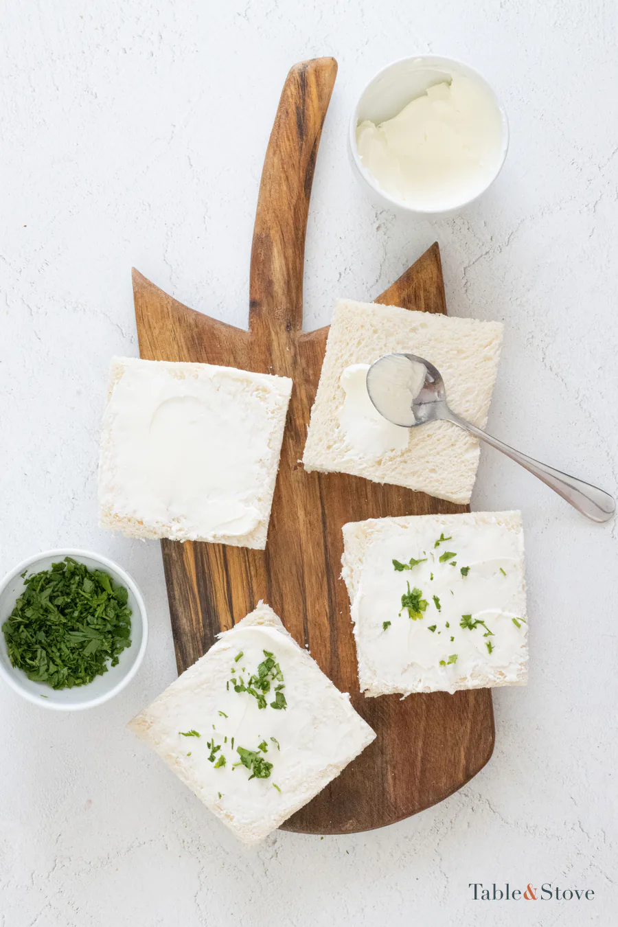 Crustless bread slices spread with cream cheese and chopped herbs