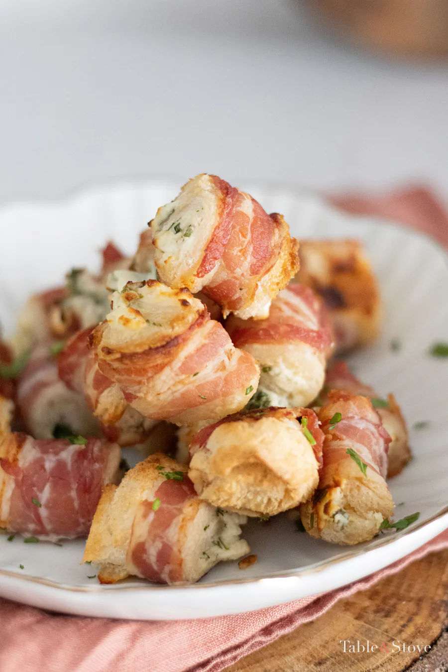 Golden bacon-wrapped cream cheese bites on a serving plate