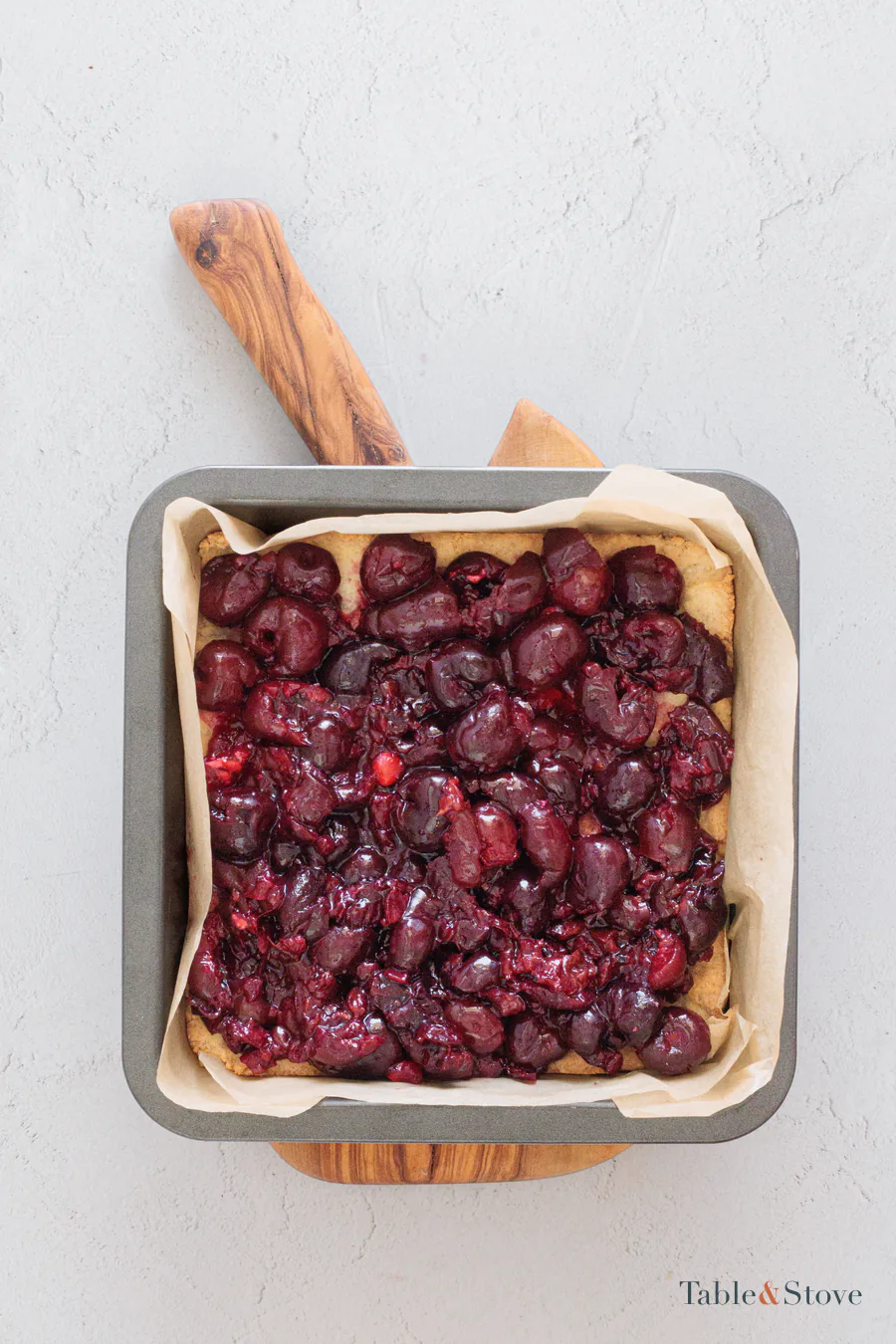 Thick cherry filling spread over a partially baked square base