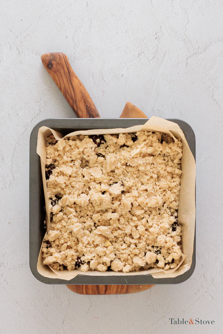 Unbaked cherry pie bars covered with loose almond crumble