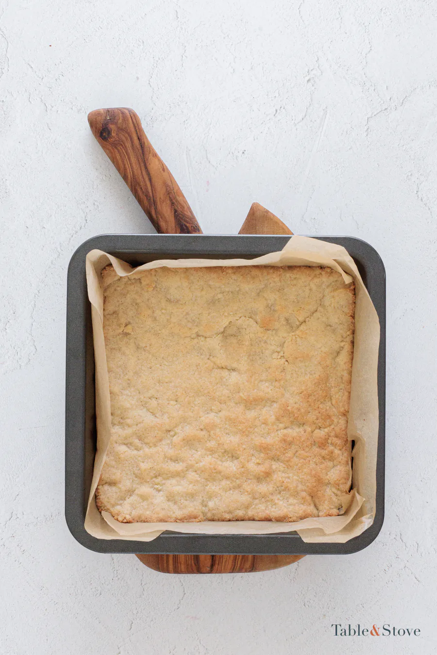 Lightly golden cherry pie bar base in a parchment-lined pan