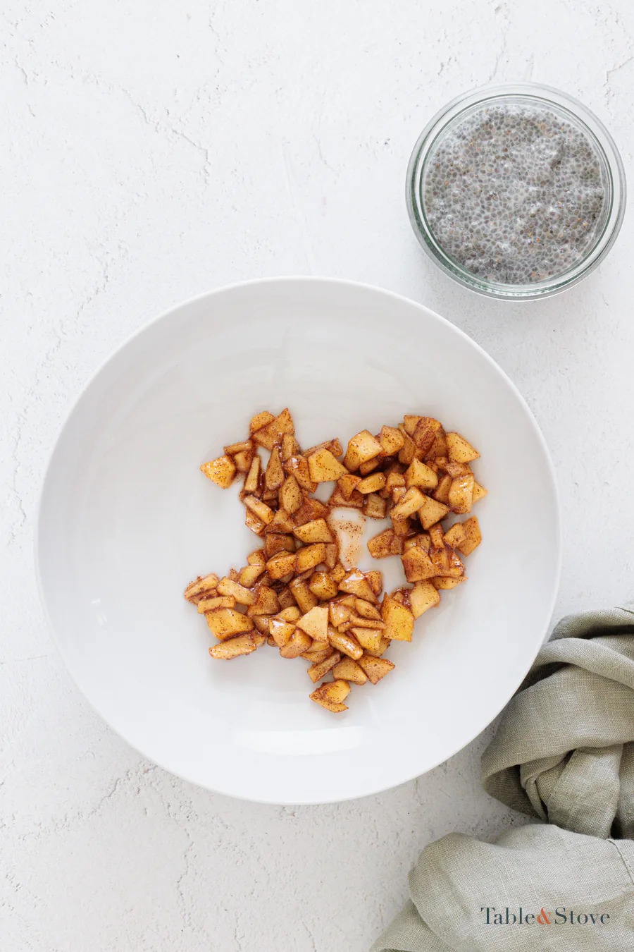 Cooked apple cubes coated with cinnamon on a white plate