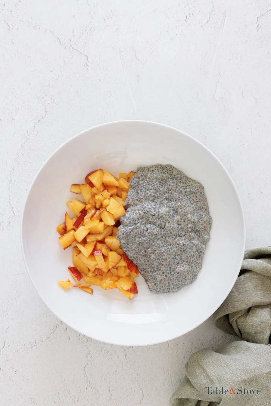 Prepared chia pudding beside diced peach pieces on a white plate