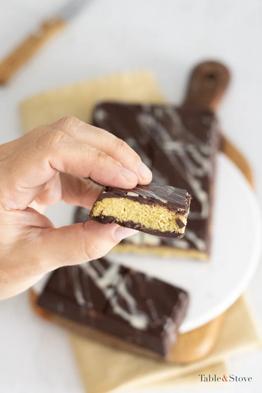 Hand holding a cut piece of Dubai chocolate to show the pistachio kataifi center