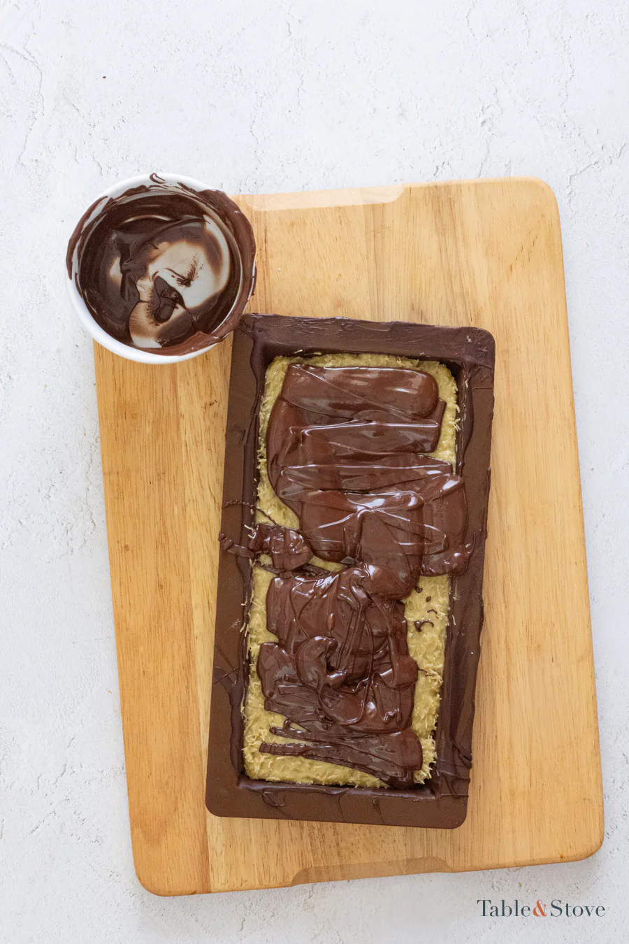 Dark chocolate being spread over pistachio kataifi filling in a mold