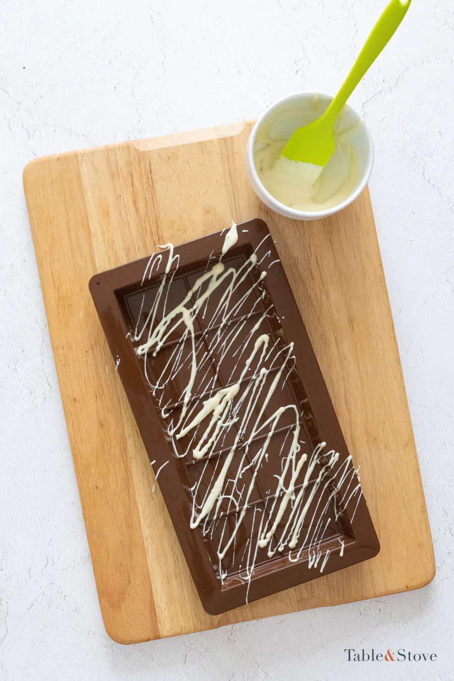 White chocolate drizzled in irregular lines across a chocolate bar mold