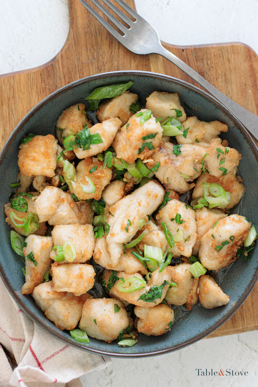 Garlic butter chicken bites served in a dark bowl with green onion and parsley