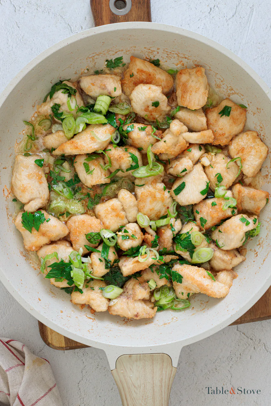 Chicken bites coated in pan sauce with chopped green onion and parsley