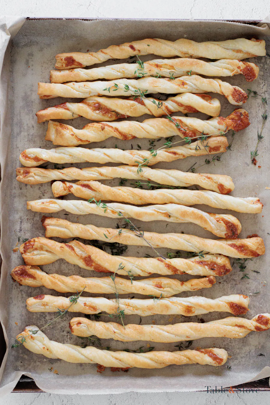 Golden baked garlic Parmesan puff pastry twists on a lined tray