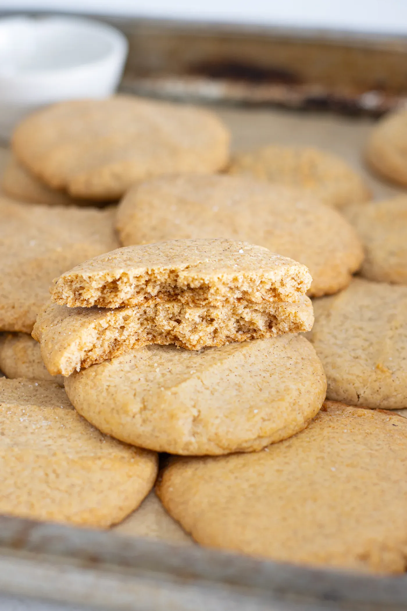 Broken honey cinnamon cookie showing its soft interior beside baked cookies