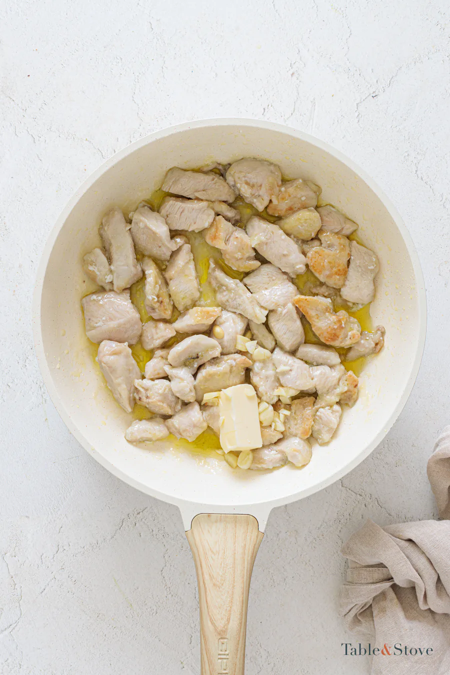 Turned chicken pieces in a skillet with butter melting among them