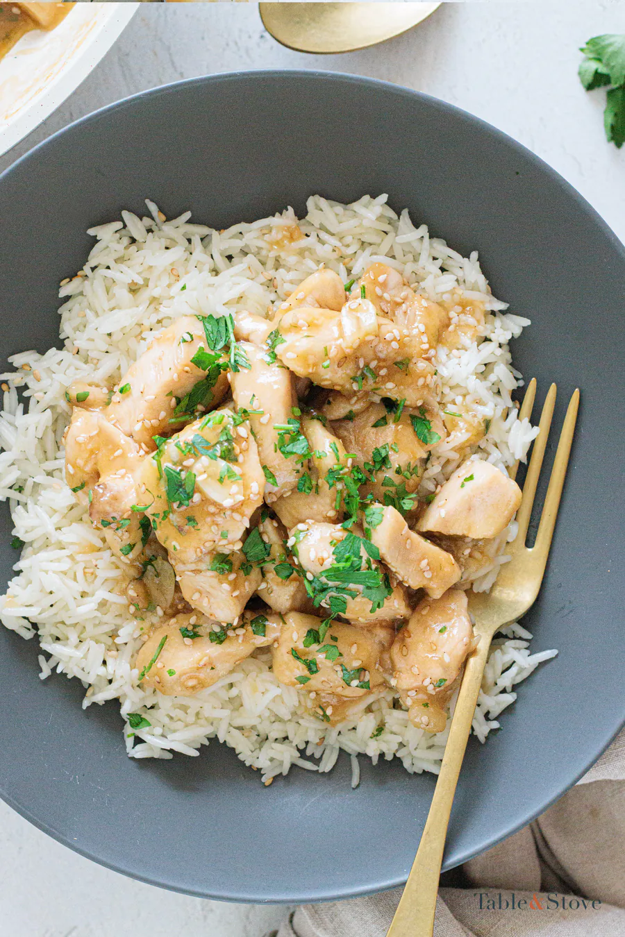 Honey garlic chicken pieces in a glossy sauce with parsley and sesame seeds