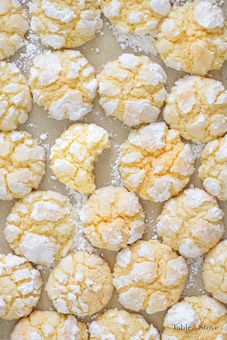 Lemon cookie dough balls coated in powdered sugar on a baking sheet