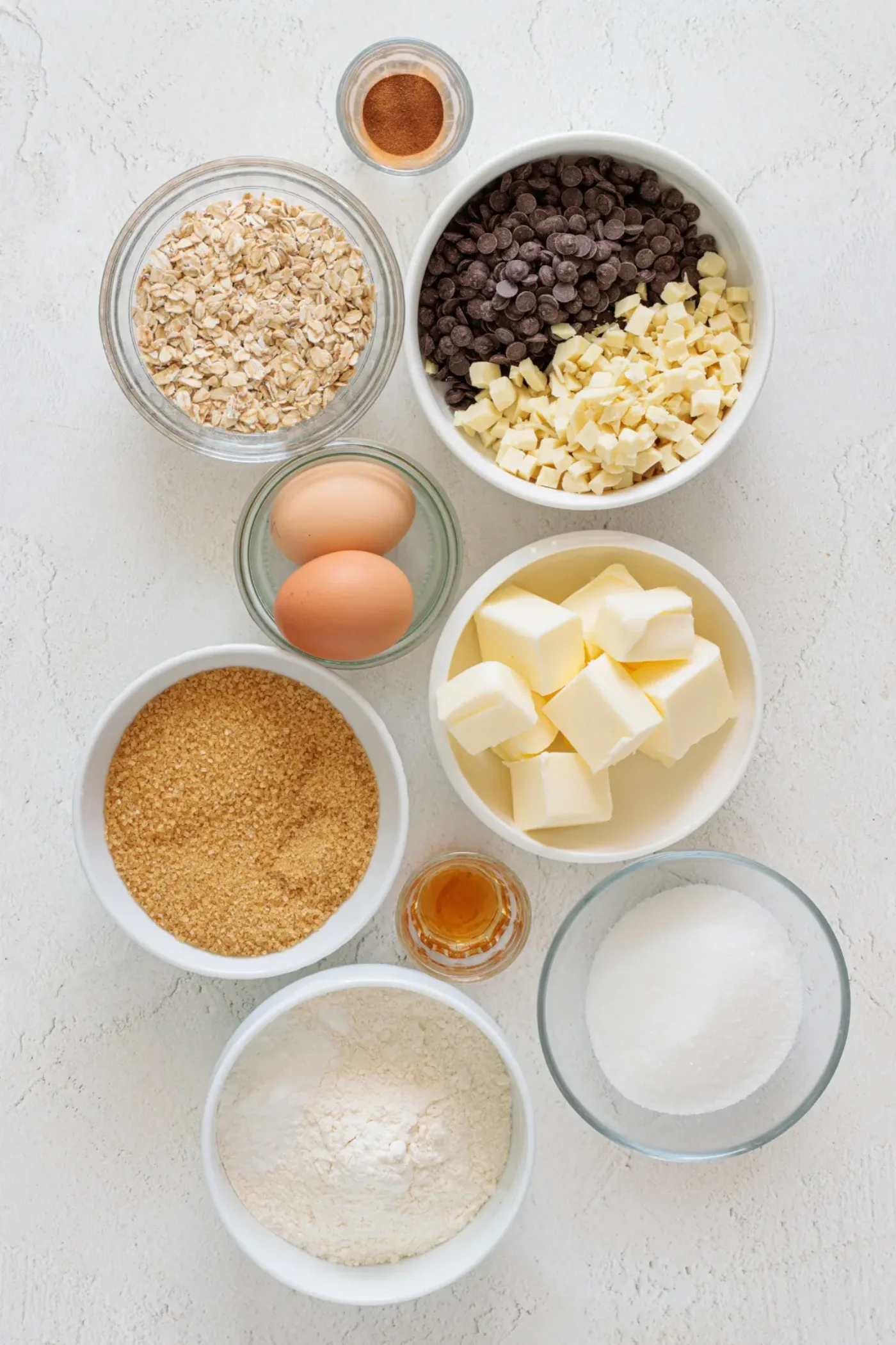 Measured ingredients for brown butter cookies, including oats, chocolate, butter, sugars, eggs, flour, cinnamon, and vanilla