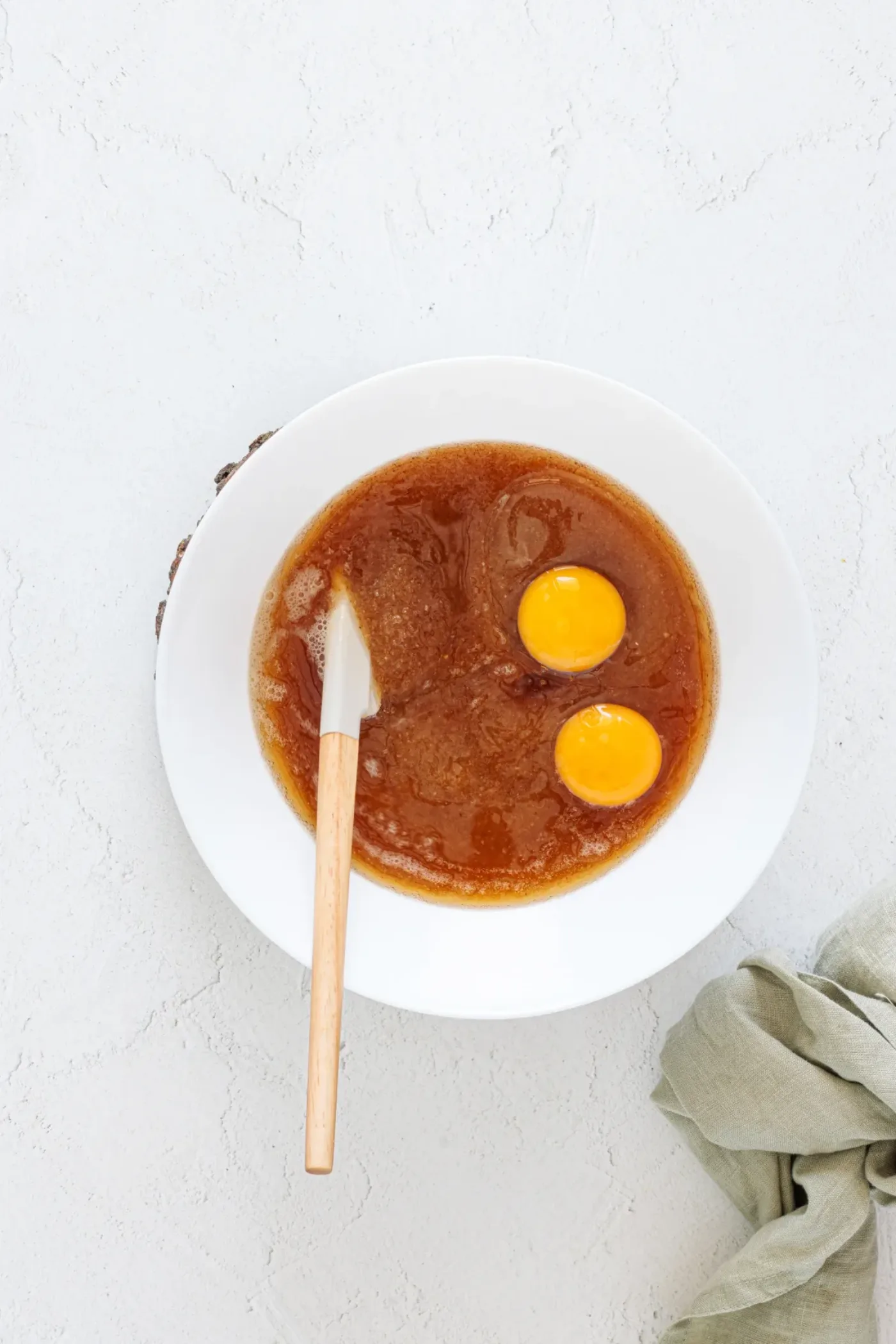 Eggs added to a bowl of cooled brown butter and sugar mixture