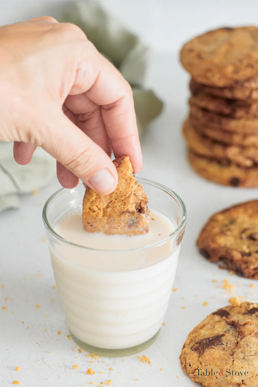 Hand dipping a piece of oat cookie into a glass of milk
