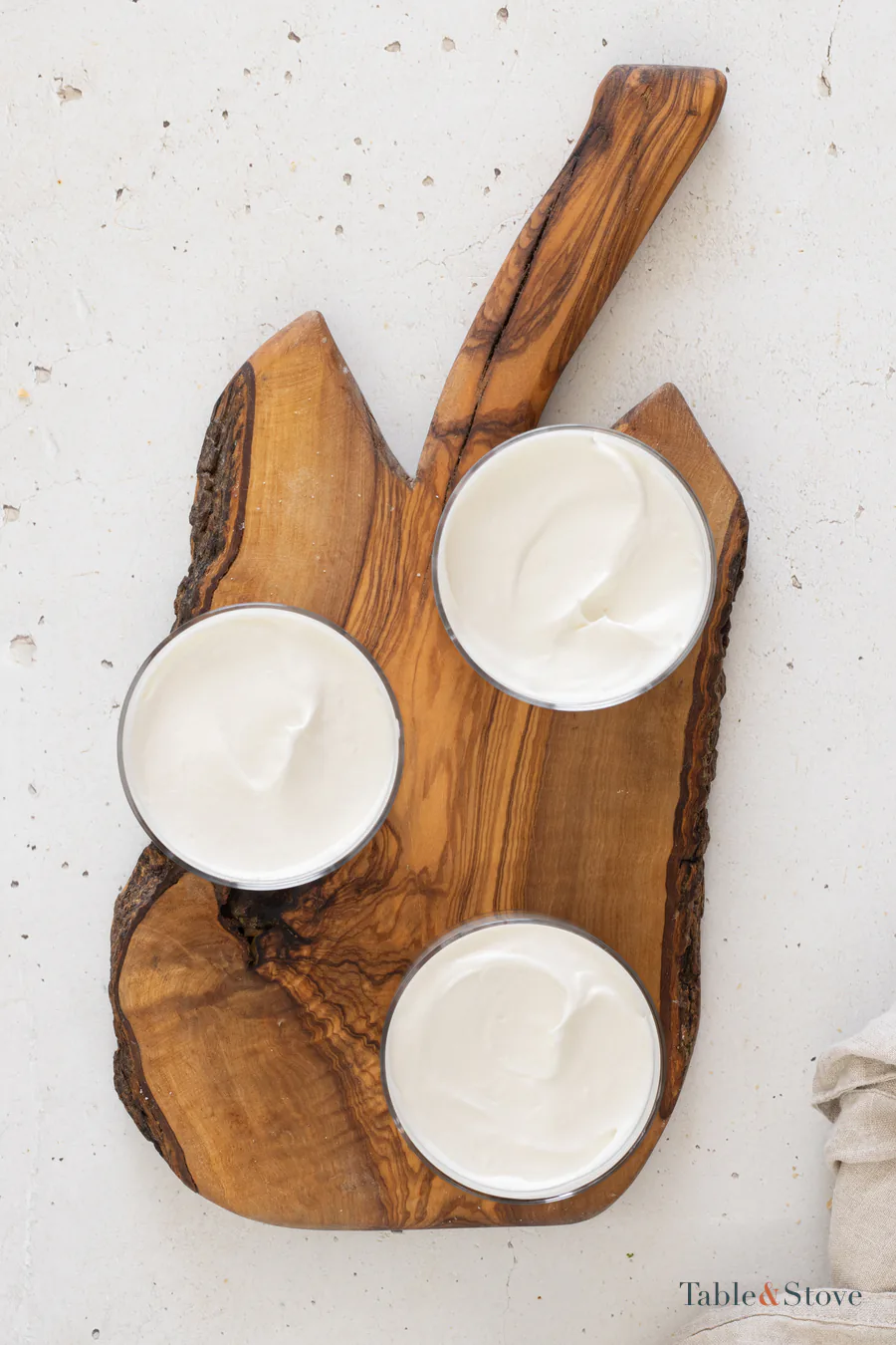 Three serving glasses filled with smooth cheesecake mixture over cookie bases