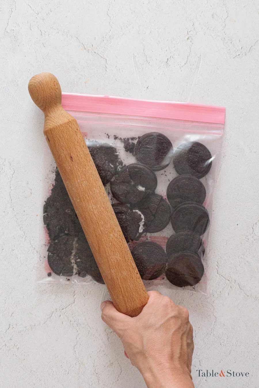 Oreo cookies being crushed inside a sealed bag with a rolling pin