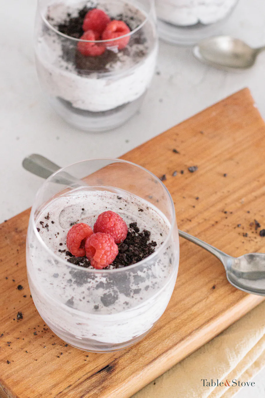 No-bake Oreo dessert cups topped with raspberries and cookie crumbs