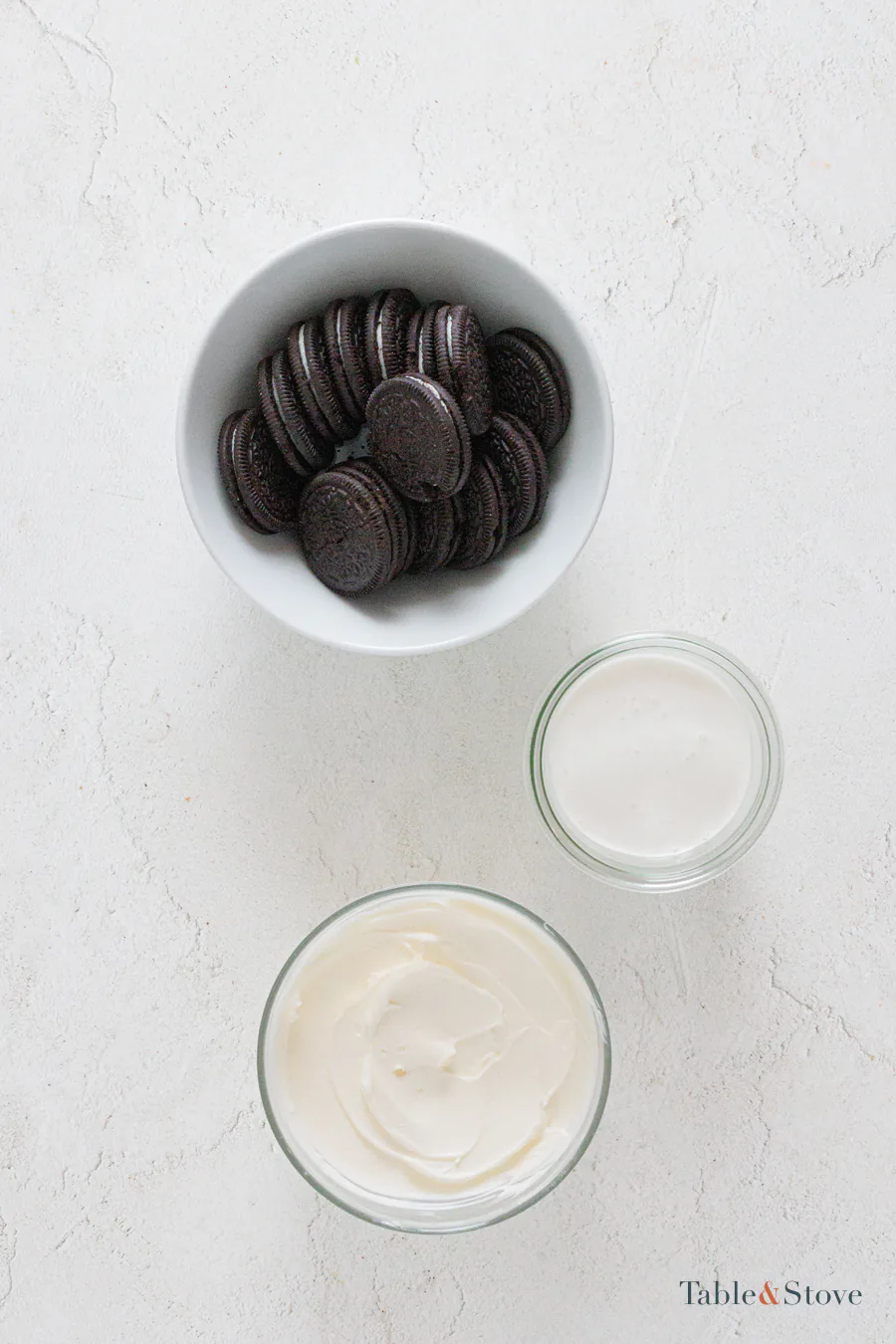 Oreo cookies, cream cheese, and whipping cream arranged in bowls