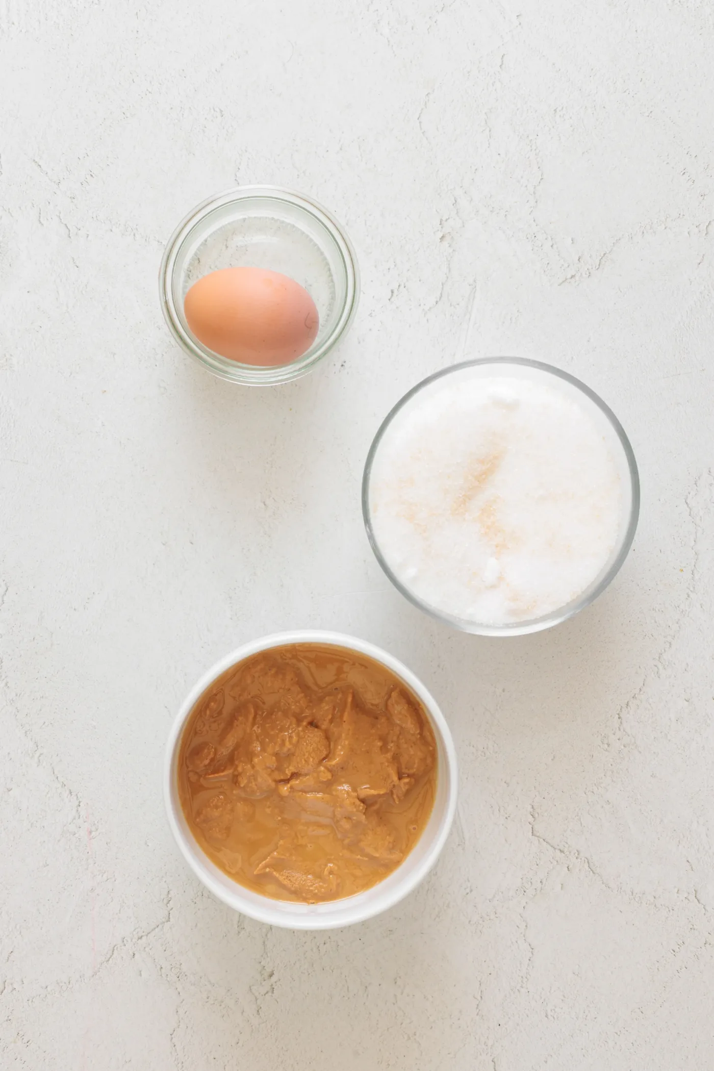 Peanut butter, granulated sugar, and an egg measured for three ingredient peanut butter cookies
