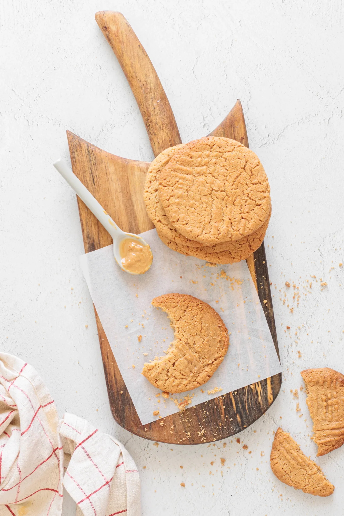 Baked peanut butter cookies on a wooden board with one broken cookie