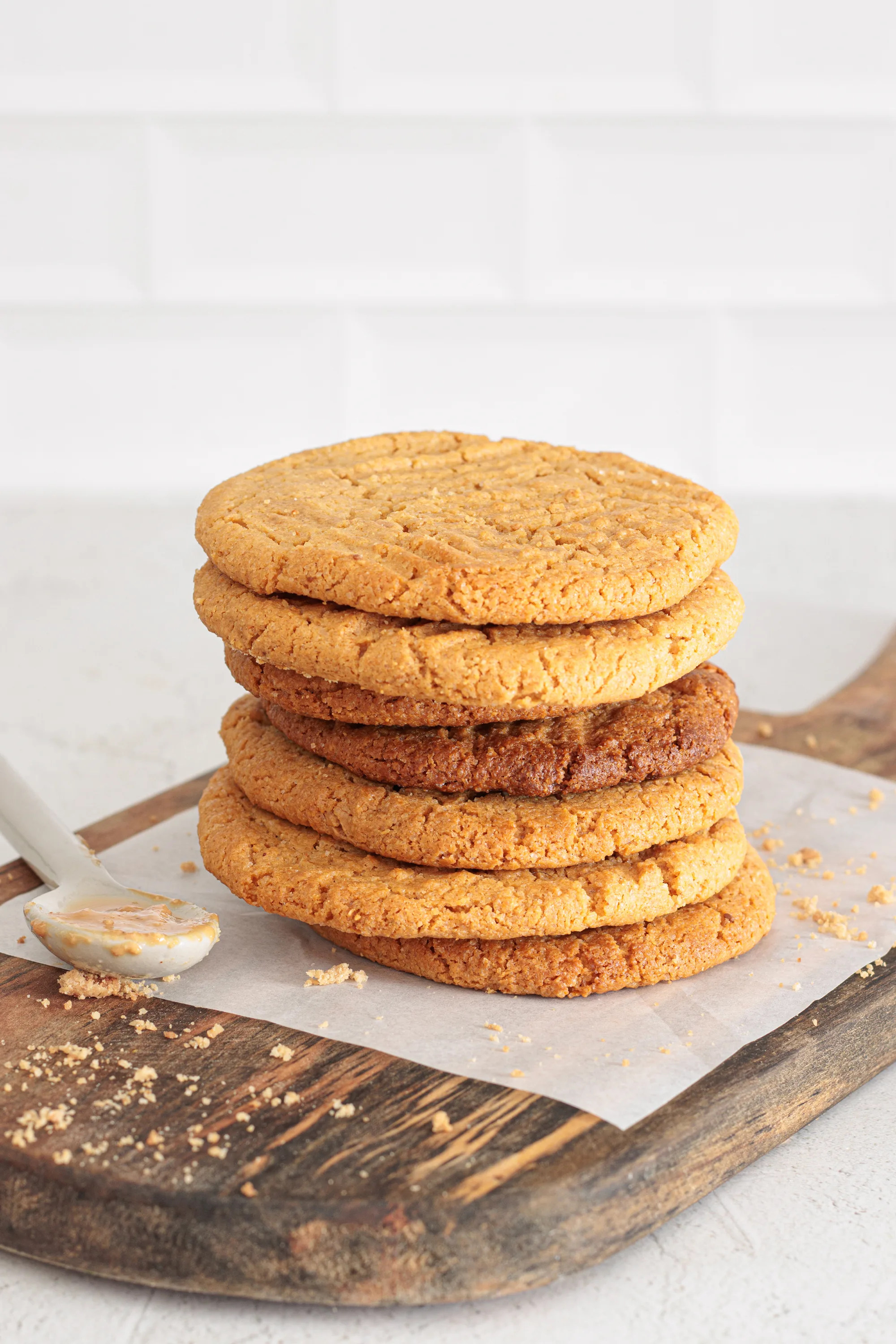 Stack of golden three ingredient peanut butter cookies on a wooden board