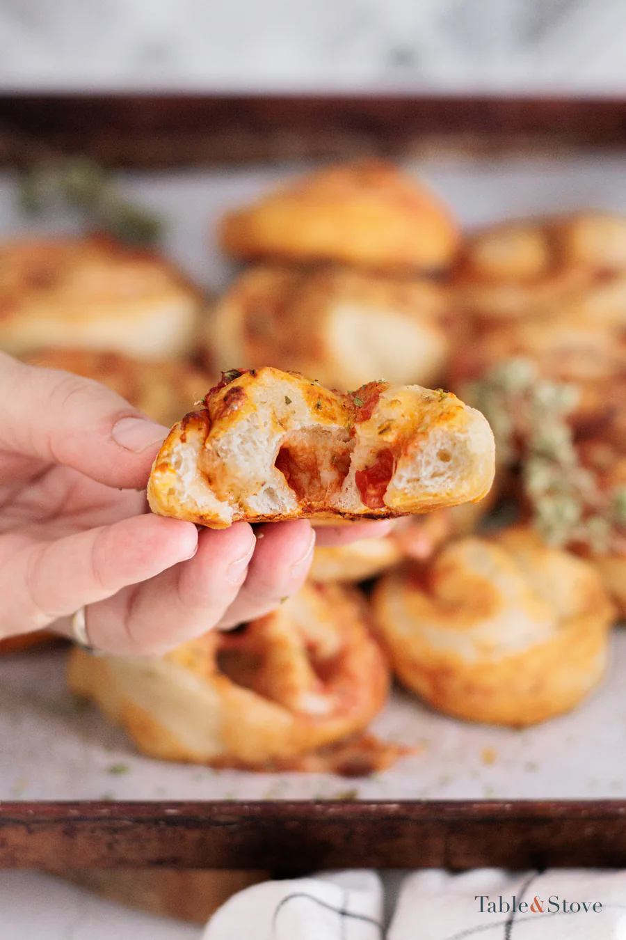 Hand holding a split pizza pinwheel to show the soft spiral inside