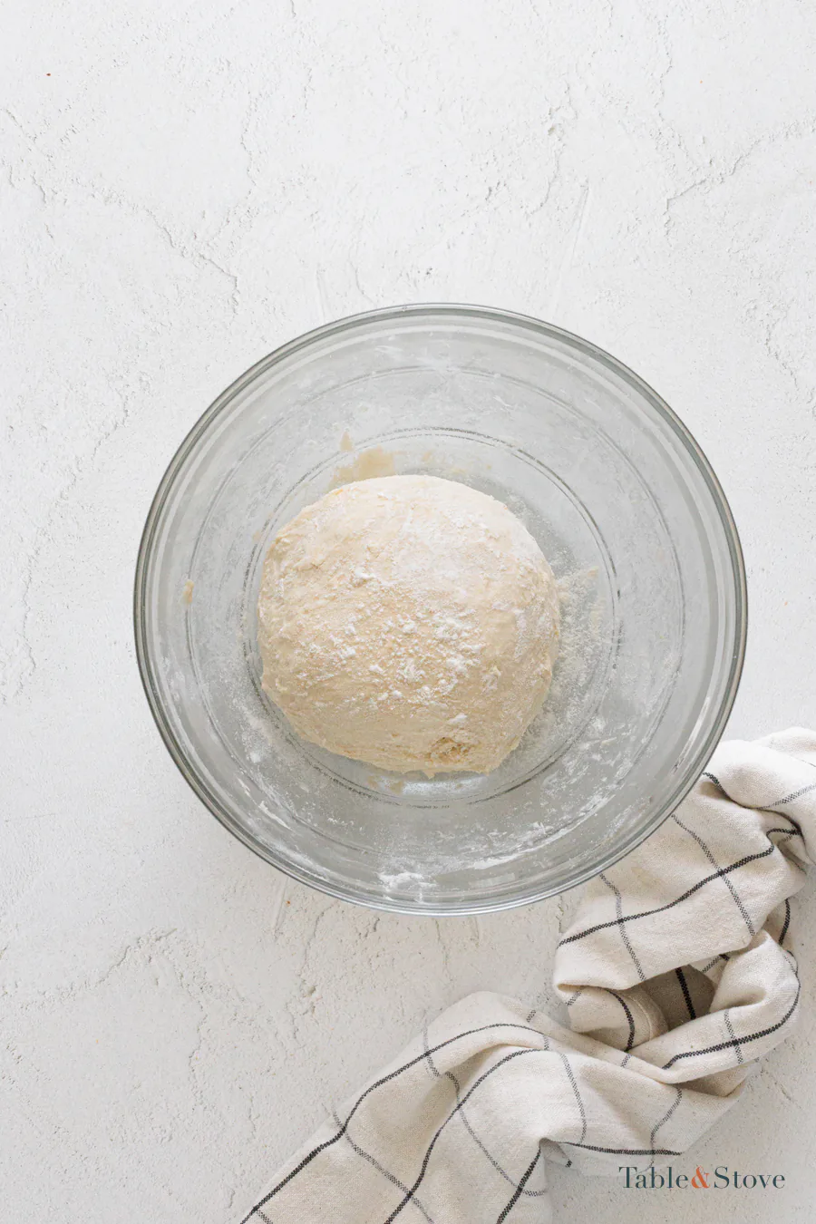Smooth risen pizza dough in a glass bowl