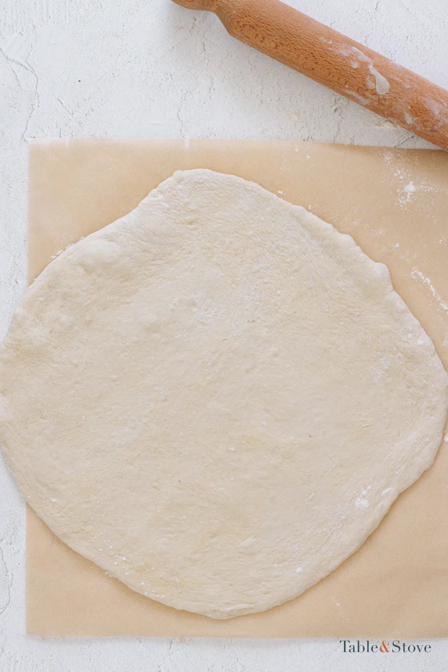 Pizza dough rolled into a thin rectangle on parchment paper