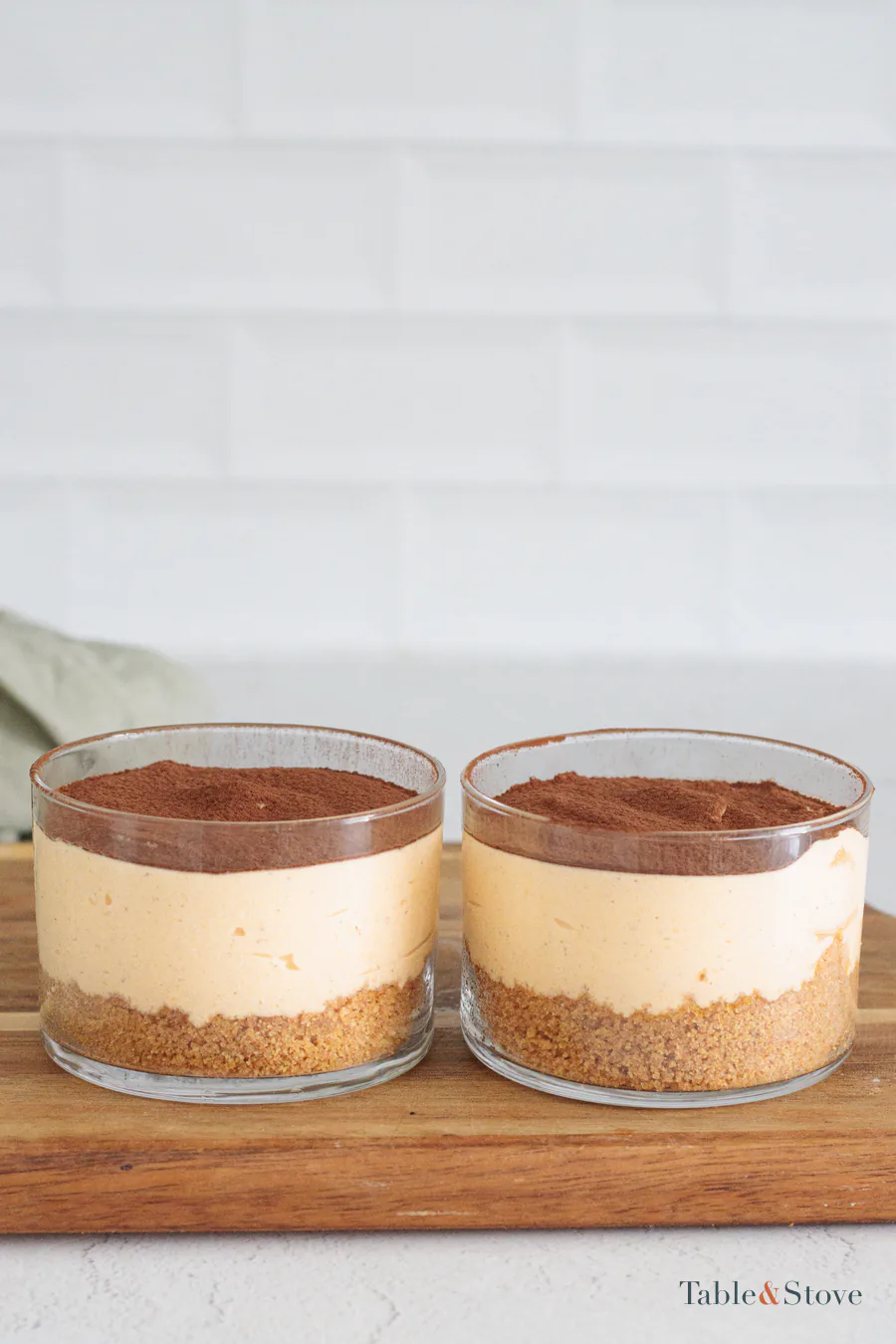 Side view of pumpkin cheesecake cups with cocoa on top and cookie bases underneath