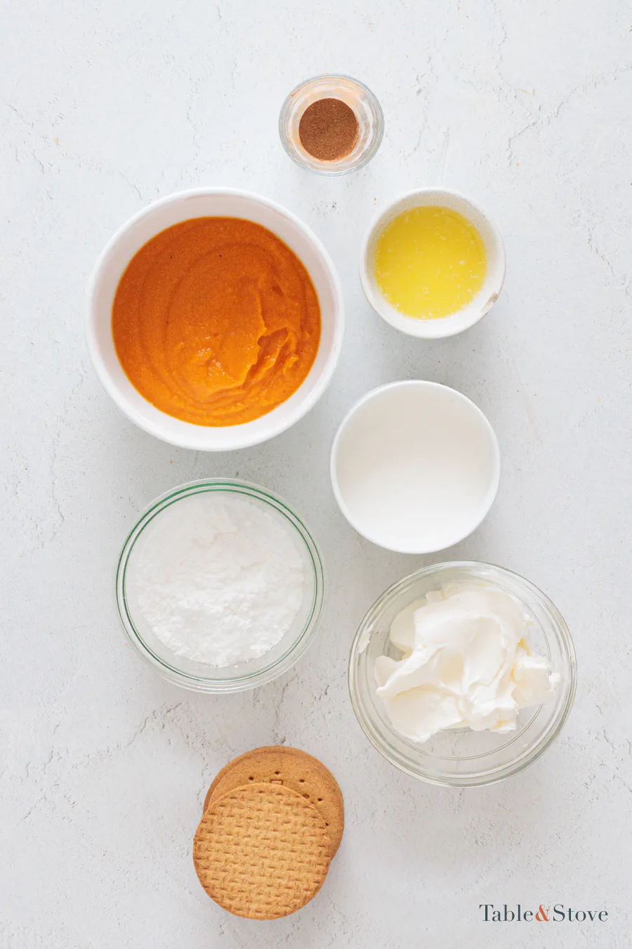 Cookies, butter, cream cheese, pumpkin puree, whipping cream, powdered sugar, and cinnamon set out for the cheesecake cups
