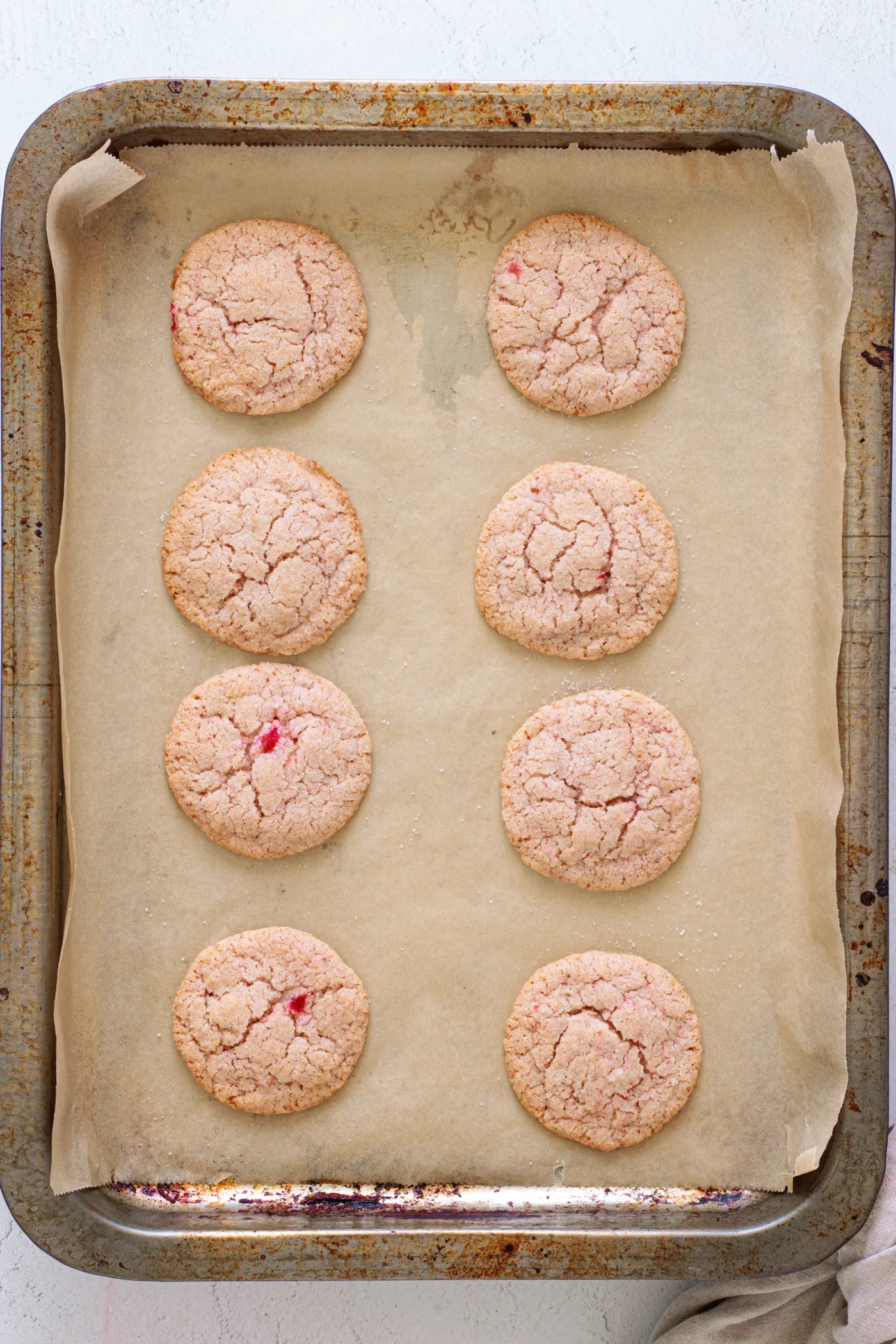 Sugar-coated strawberry cookie dough balls spaced on a parchment-lined baking sheet