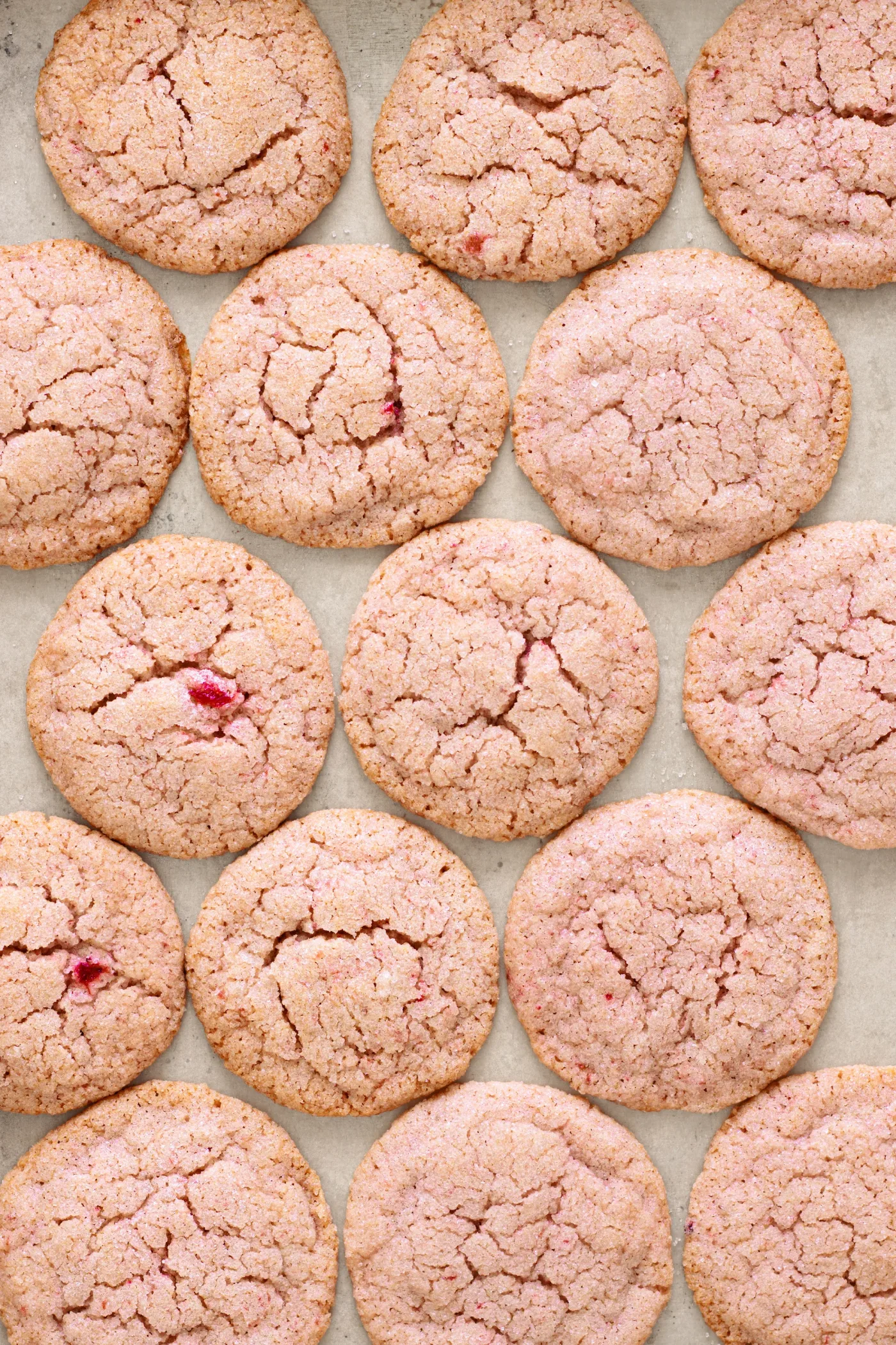 Baked strawberry sugar cookies with crackled tops on a parchment-lined baking sheet